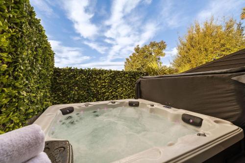 a hot tub in a backyard with a hedge at Distinctive Alpine Meadows in Queenstown