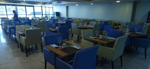 a dining room with tables and blue chairs at Flat no Beach Class Internacional, à beira-mar, em Boa Viagem, Recife-PE, com portaria e restaurante 24h - ideal para concursos, turismo, visto americano e jogos da série A - Piscina em reforma in Recife