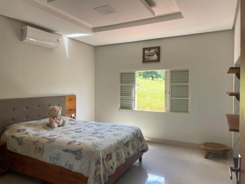 a teddy bear sitting on a bed in a bedroom at Casa Goulart in Capitólio