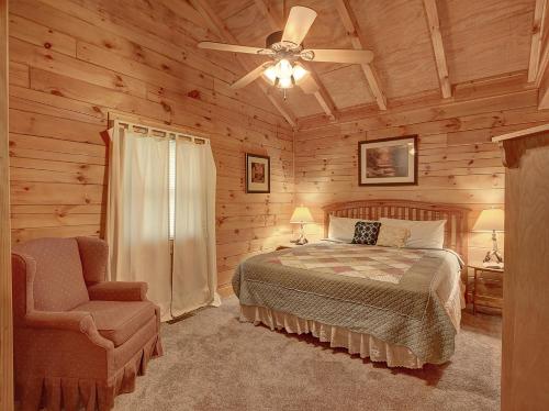 une chambre avec un lit, un ventilateur de plafond et une chaise dans l'établissement 1BR log cabin- cozy, hot tub, in Gatlinburg, à Gatlinburg