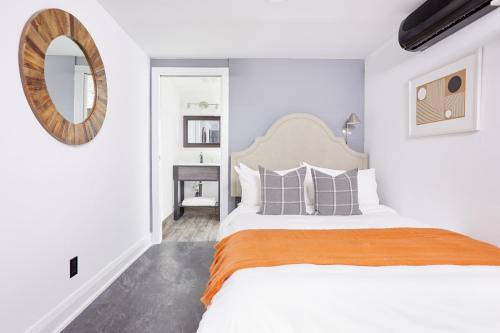 a white bedroom with a large bed and a mirror at La TUMU in Toronto