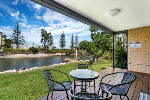 a patio with a table and chairs and a pond at Canal Luxury Living & Boat Ramp in Gold Coast