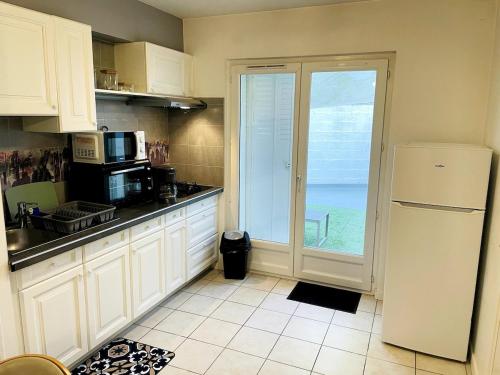 une cuisine avec un réfrigérateur et une porte coulissante en verre dans l'établissement l 'Escapade Atlantique, à Saint-Nazaire