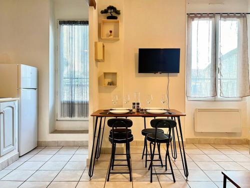 a kitchen with a table with chairs and a tv at Creux de l'Église - 2 Appartements cosy, 2 Salles de Bains, 8 personnes in Saint-Chamas