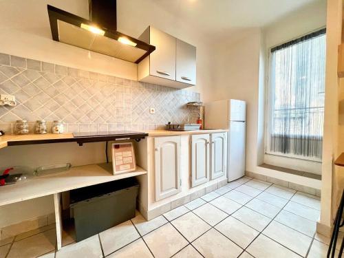 a kitchen with white cabinets and a large window at Creux de l'Église - 2 Appartements cosy, 2 Salles de Bains, 8 personnes in Saint-Chamas