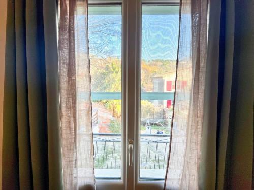 a window with curtains looking out at a view at Creux de l'Église - 2 Appartements cosy, 2 Salles de Bains, 8 personnes in Saint-Chamas