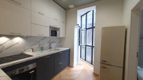 une cuisine avec des placards blancs et une grande fenêtre dans l'établissement Appartement d'architecte au coeur de Bordeaux, à Bordeaux