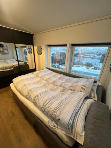 a bedroom with a large bed with two windows at My Home Kaldfjorden in Tromsø