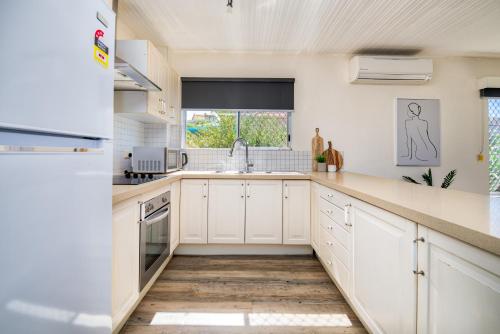 a kitchen with white cabinets and a sink at Canal Luxury Living & Boat Ramp in Gold Coast