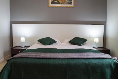 a bedroom with a large bed with two green pillows at B&B Da Vinci in Matera