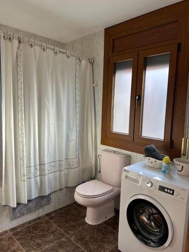 a bathroom with a toilet and a washing machine at Casa en el Balcón del Pirineo in Montferrer