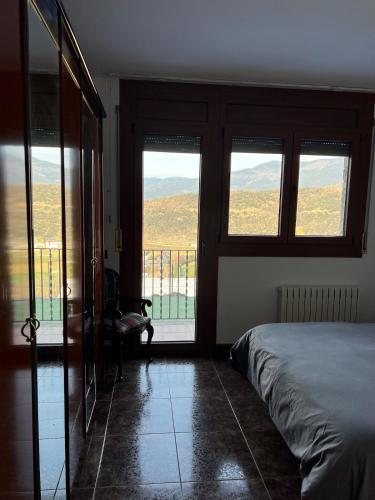 a bedroom with a bed and windows with a view at Casa en el Balcón del Pirineo in Montferrer