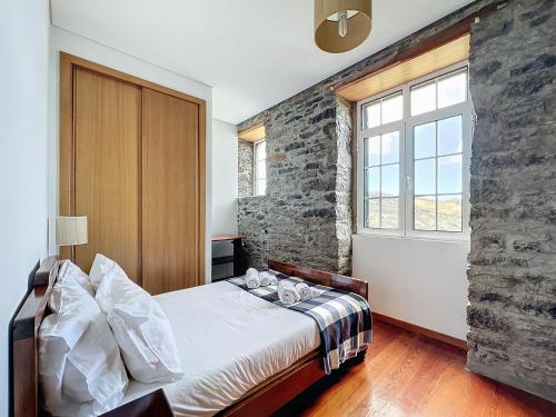 ein Schlafzimmer mit einem Bett und einer Steinwand in der Unterkunft Quinta do Serrado in Porto Moniz