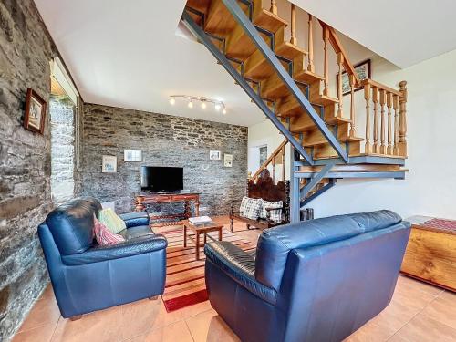 a living room with two blue chairs and a staircase at Quinta do Serrado in Porto Moniz
