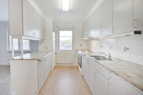 a white kitchen with white cabinets and a sink at Central two-room apartment with a large balcony in Junsele