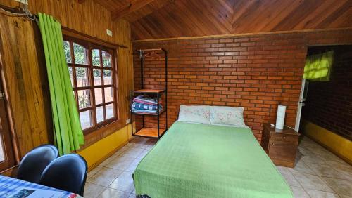a bedroom with a green bed in a brick wall at Cabañas Rincon Santa Maria in Puerto Iguazú