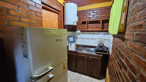 a kitchen with a refrigerator and a brick wall at Cabañas Rincon Santa Maria in Puerto Iguazú