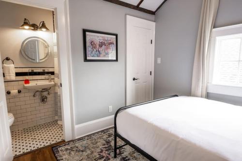 a bedroom with a bed and a bathroom with a sink at Mandeville Creole Cottage - 3 bed-2 bath in New Orleans