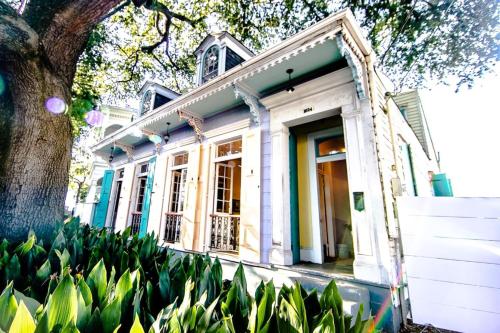 a white house with a tree and some plants at Governors Mansion 5 bedroom-3 bath in New Orleans