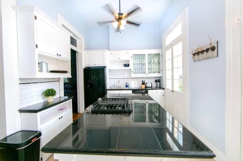 a kitchen with white cabinets and a ceiling fan at Governors Mansion 5 bedroom-3 bath in New Orleans