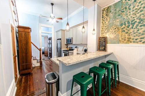 eine Küche mit einer Theke mit grünen Stühlen in der Unterkunft Ursulines Historic Creole Cottage- Steps to Qtr -E in New Orleans