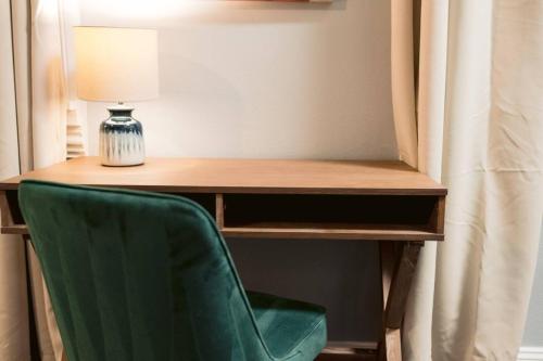 a green chair sitting in front of a desk with a lamp at Monthly - Dumaine Historic Carriage House in New Orleans