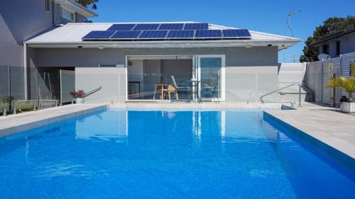 a house with a swimming pool with solar panels on the roof at HIBBARD HAVEN in Port Macquarie