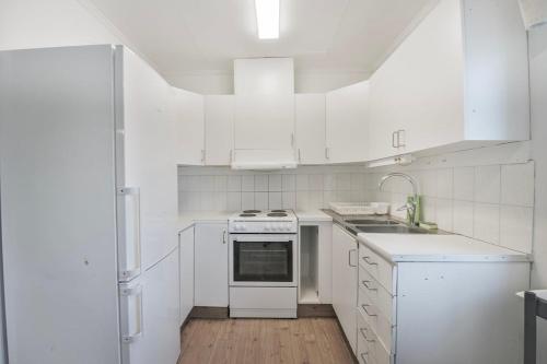 a white kitchen with white appliances and a wooden floor at Central 2 room apartment in Junsele in Junsele