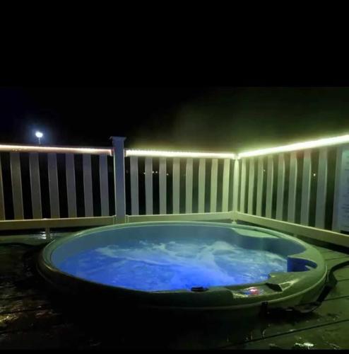 a jacuzzi tub in front of a fence at night at Luxury Caravan with Hot tub on Tattershall lakes in Lincoln