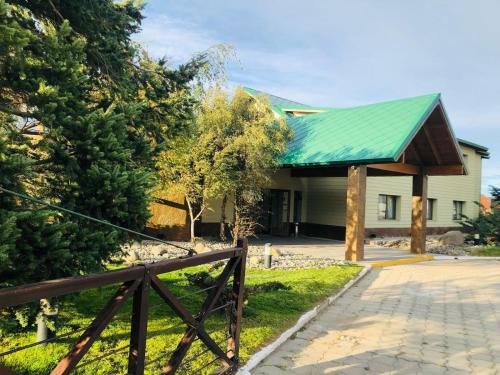 a house with a green roof and a fence at Konke Calafate Hotel in El Calafate