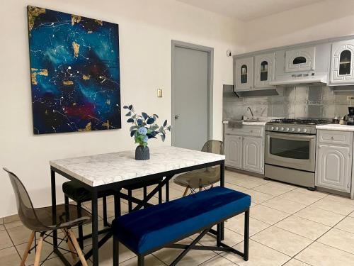 eine Küche mit einem Tisch, Stühlen und einem Gemälde in der Unterkunft Agradable depto con estacionamiento y portón eléctrico in Guasave