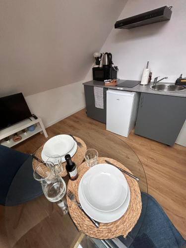 une table avec deux assiettes blanches et des verres dans l'établissement Cozy studio 5, à Saint-Quentin