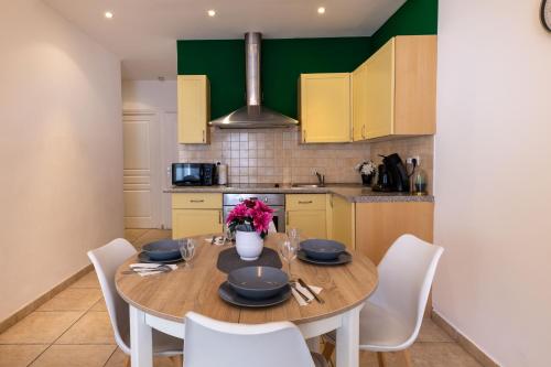 - une cuisine avec une table en bois et des chaises blanches dans l'établissement Joli cocon à 3 min à pied de la mer, à Nice