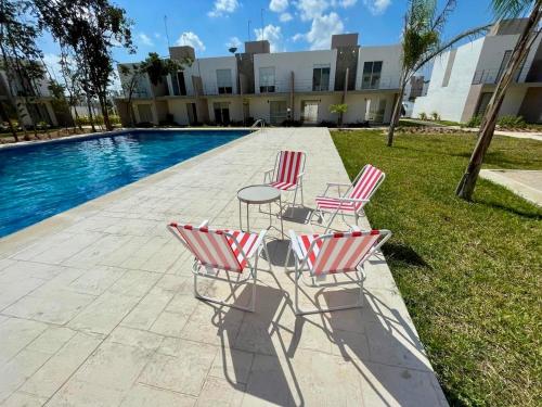 a group of chairs and a table next to a pool at Linda casa frente a alberca en Playa del Carmen in Playa del Carmen
