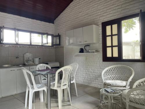 a kitchen with white chairs and a table and a counter at Hotel - Apart-hotel Chalé Executivo in Mossoró