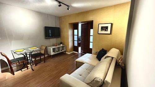 a living room with a white couch and a table at Apartamento completo no Centro de Nova Friburgo in Nova Friburgo