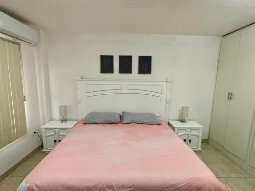 a white bedroom with a large bed with two tables at Cómodo y agradable departamento con estacionamiento y portón eléctrico in Guasave
