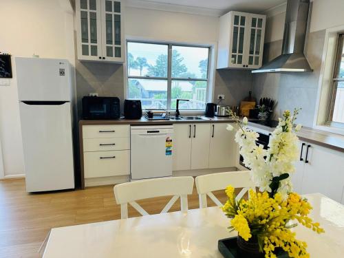 a kitchen with a white refrigerator and a table with flowers at The Bliss at Batehaven in Batehaven