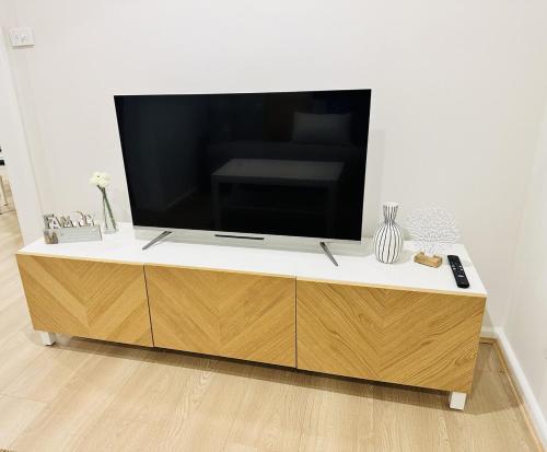 a flat screen tv sitting on top of a wooden cabinet at The Bliss at Batehaven in Batehaven