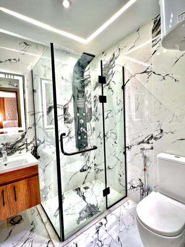 a marble bathroom with a shower and a toilet at Khofo pyramids view inn in Cairo