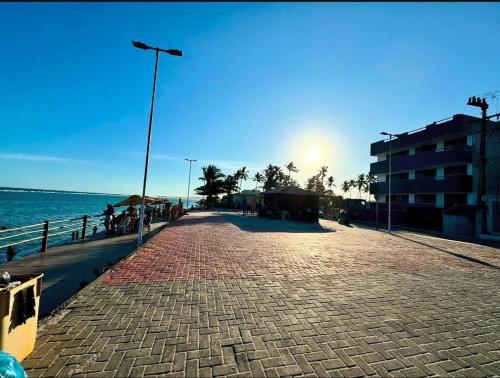a brick road next to the ocean with the sun setting at Flat Brisa da BARRA in Barra de São Miguel