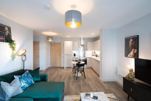 a living room with a green couch and a kitchen at Media City Salford Quays in Manchester