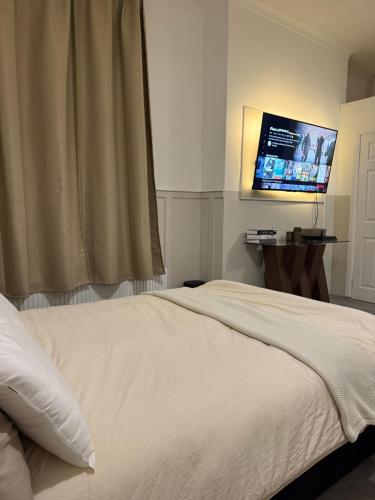 a bedroom with a white bed and a flat screen tv at City Centre Uni area PS4 Netflix in Neepsend