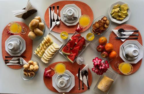 a table topped with plates of food and fruit at Pousada das Flores in Fernando de Noronha