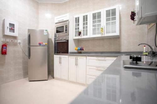 a kitchen with white cabinets and a stainless steel refrigerator at Hayatt Ula Suite - 104 in AlUla