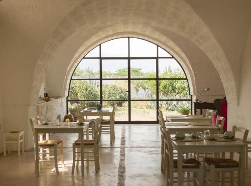 オストゥーニにあるMasseria Palombara Grandeのテーブルと椅子、大きな窓が備わる客室です。