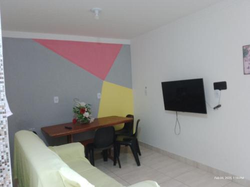 un salon avec une table et une télévision dans l'établissement Casa temporada Caípe, à São Francisco do Conde