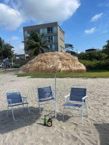 two chairs and an umbrella on the beach at Departamento al pie del mar con hermosa vista in Cautivo
