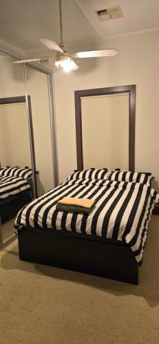 a bed with a black and white striped comforter in a room at Peaceful Haven in Adelaide