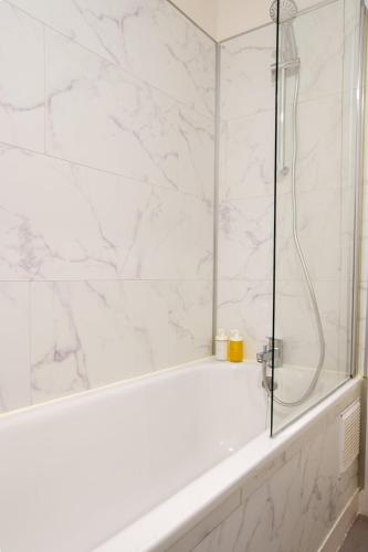 La salle de bains blanche est pourvue d'une douche et d'une baignoire. dans l'établissement Appartement Cosy douillet - Proche du Tram - Gare & Circuit 24H, au Mans